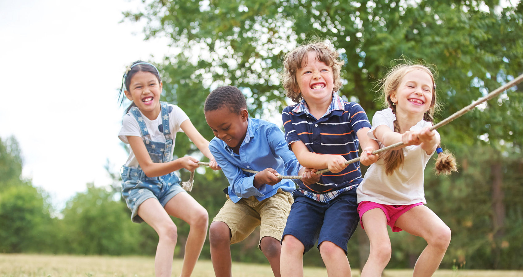 group of children is pulling a rope while smiling